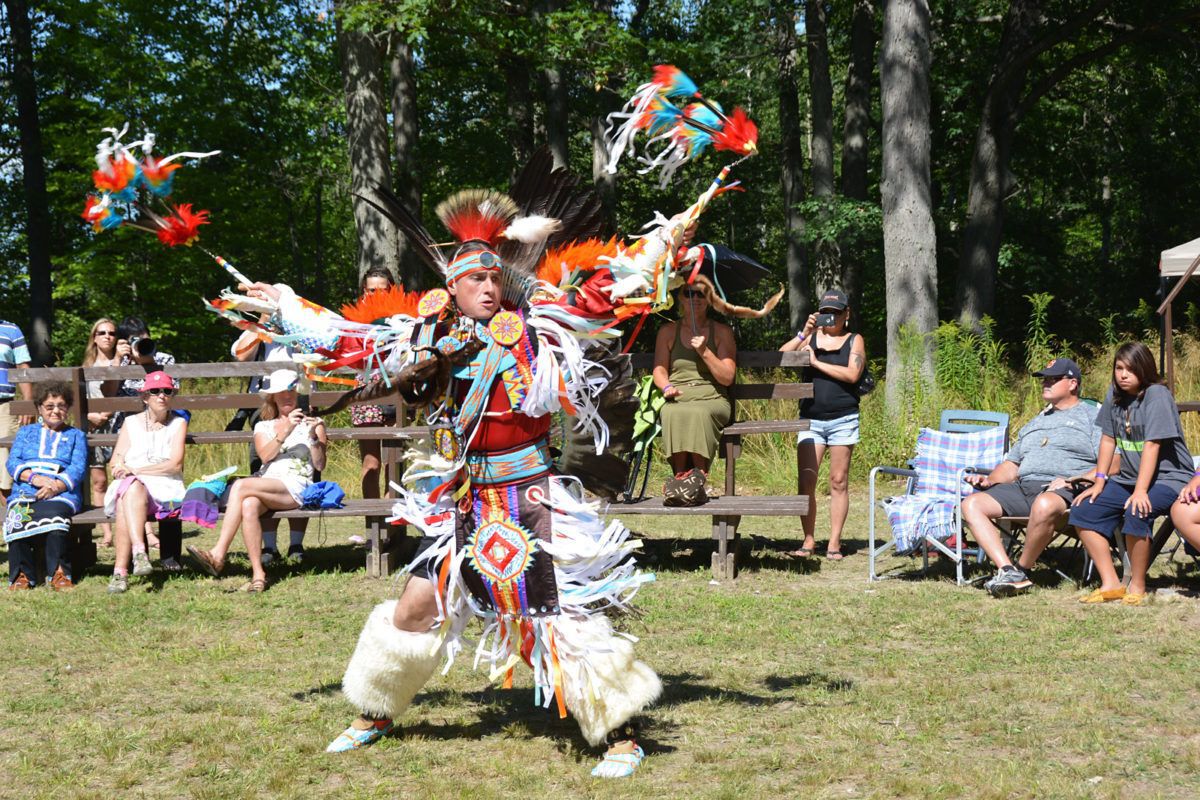 A man in pow wow regalia dances outside