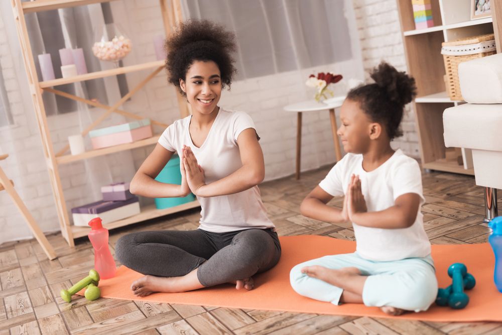 Woman and young girl sit in a yoga pose