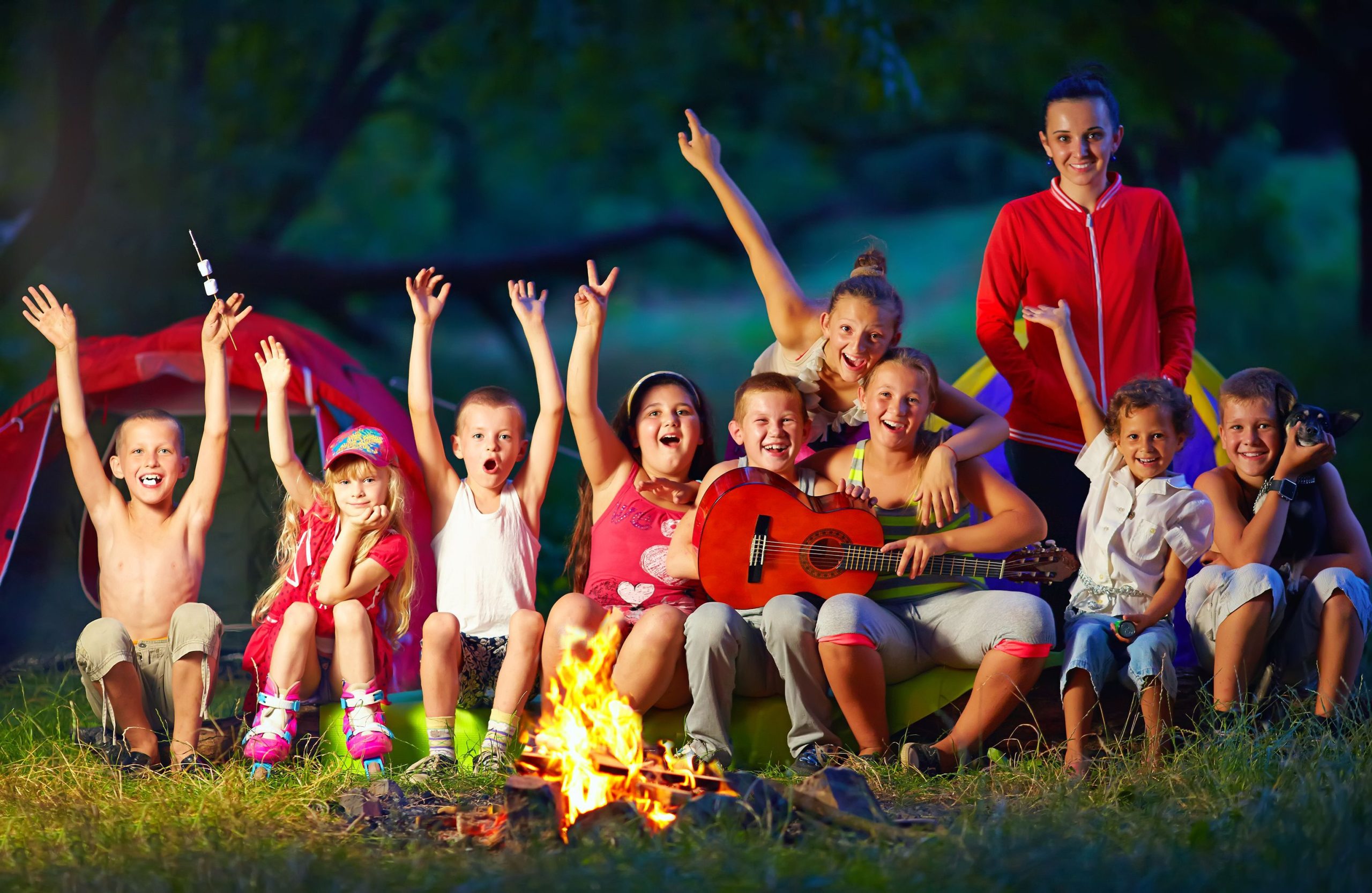 Children-and-an-older-teen-surround-a-campfire-at-dusk