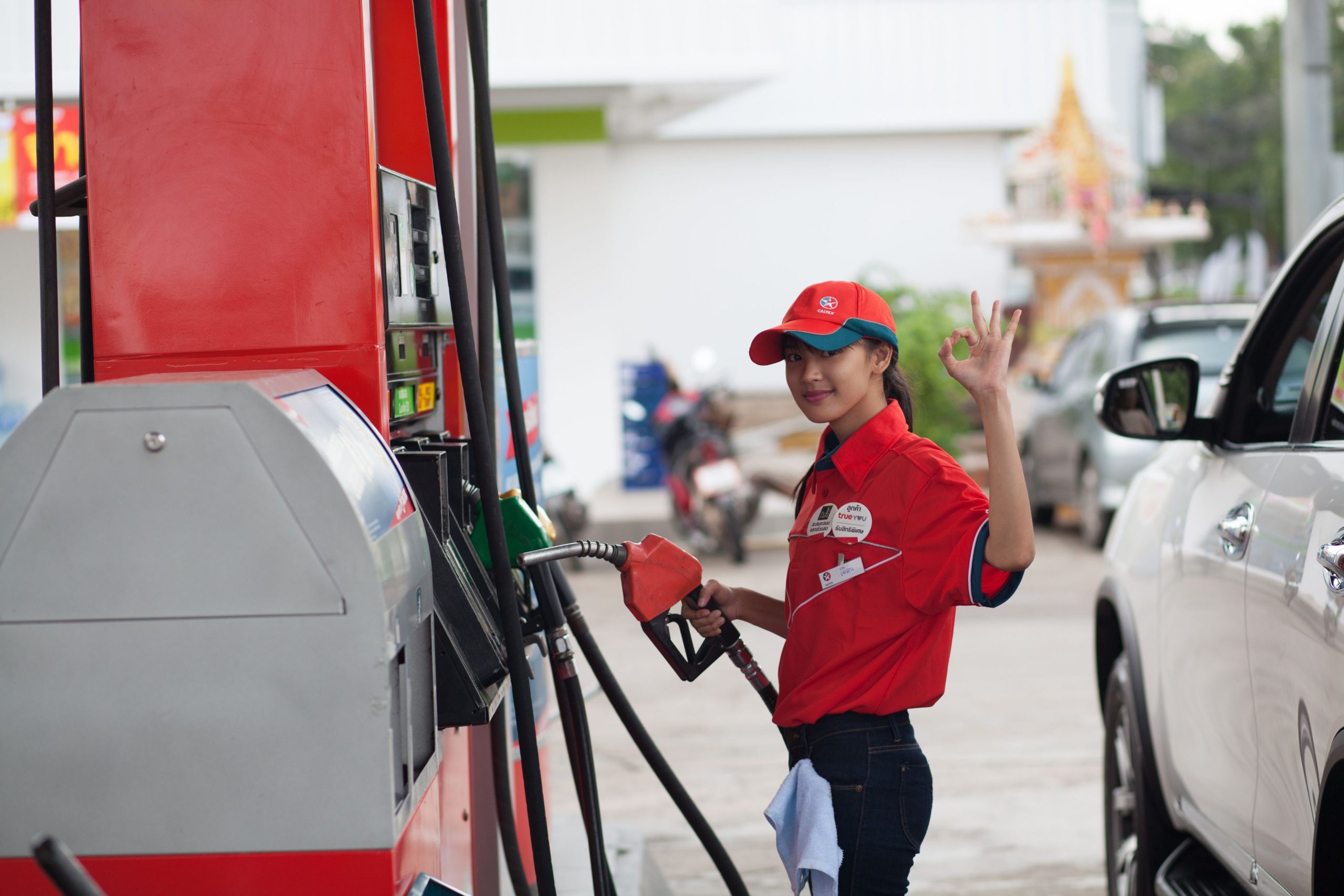 A-young-woman-pumping-gas-with-a-okay-hand-sign