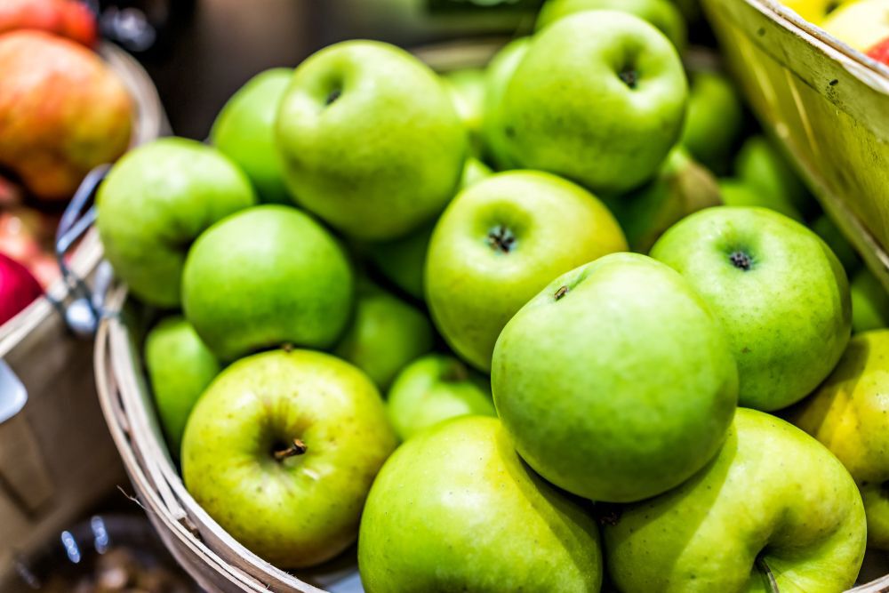A bushel of green apples at a farmers' market