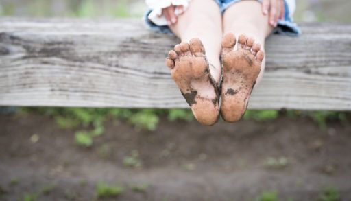 A-child-with-dirty-feet-sits-on-a-fence