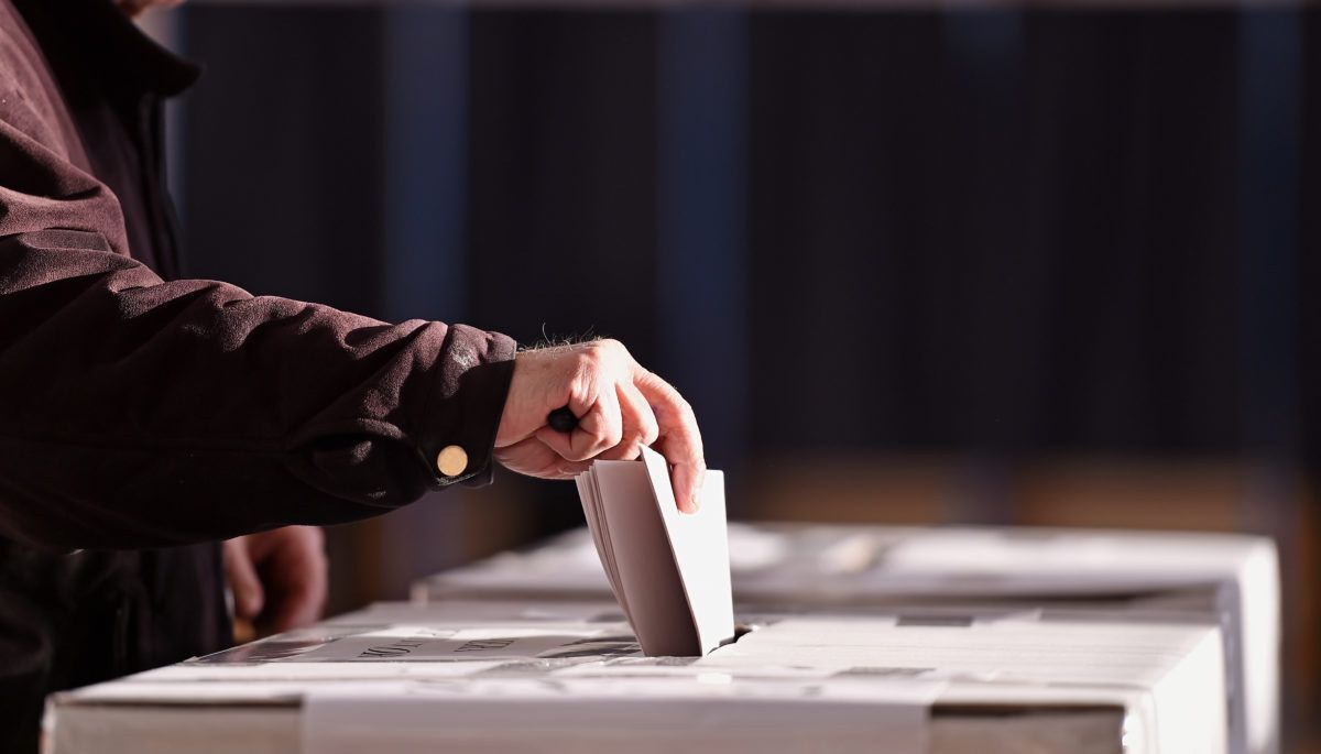 Hand of a person casting a vote into the ballot box during an election