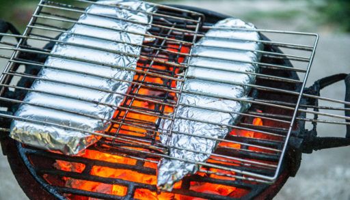 Fish fillets in aluminum foil cooking on the grill