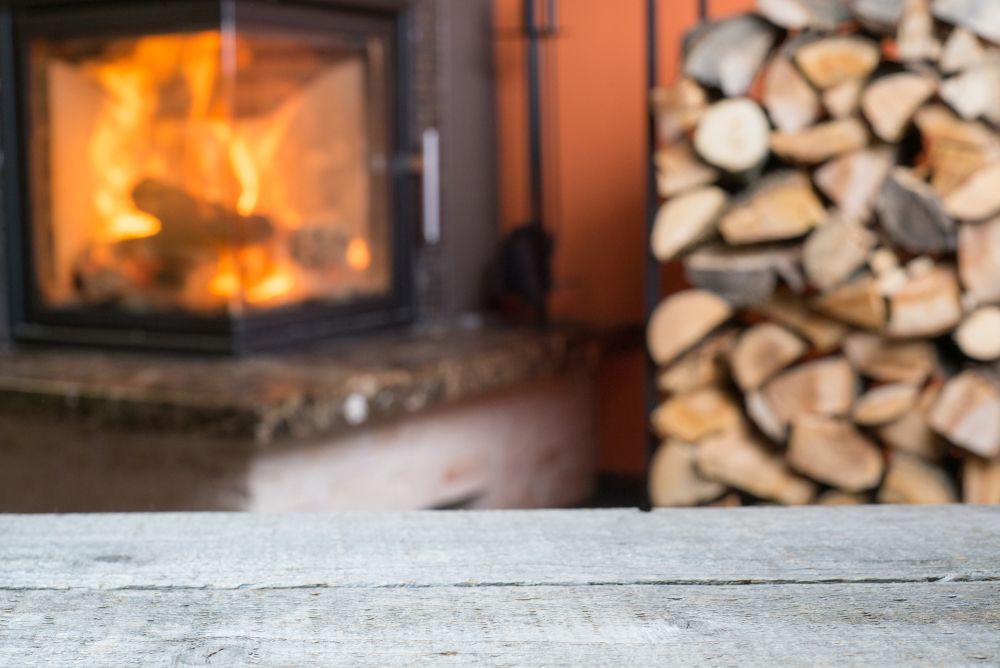 A roaring fire with a woodpile beside it