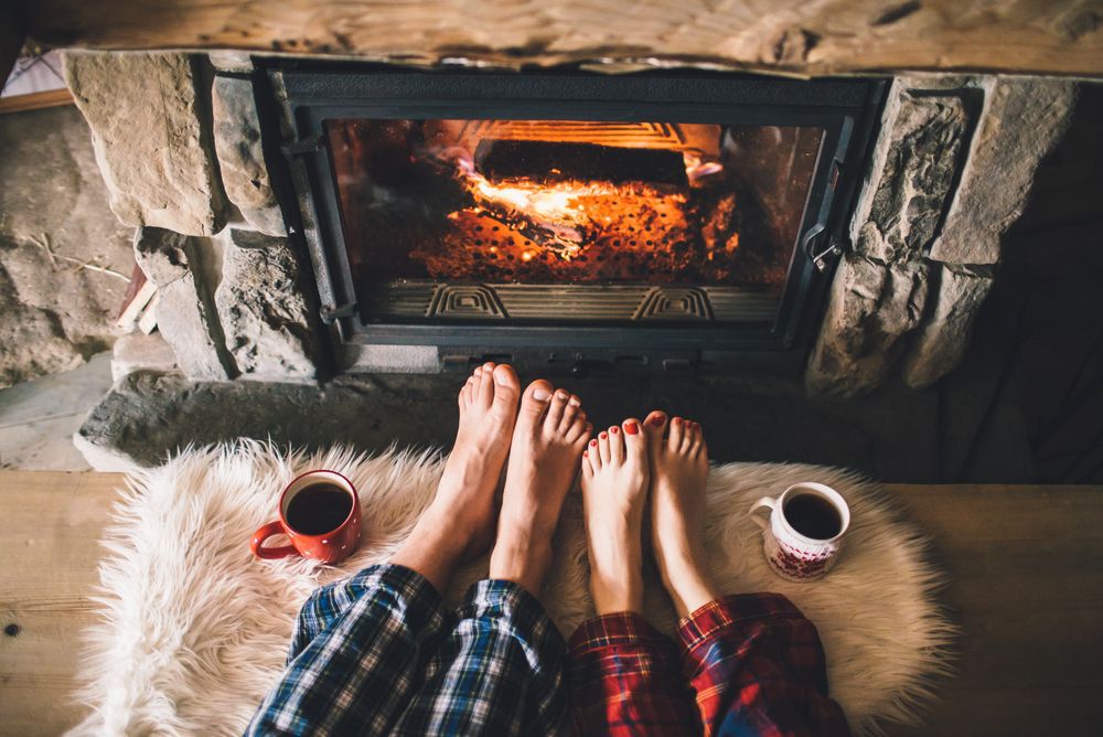 A man and woman's feet in front of a fireplace