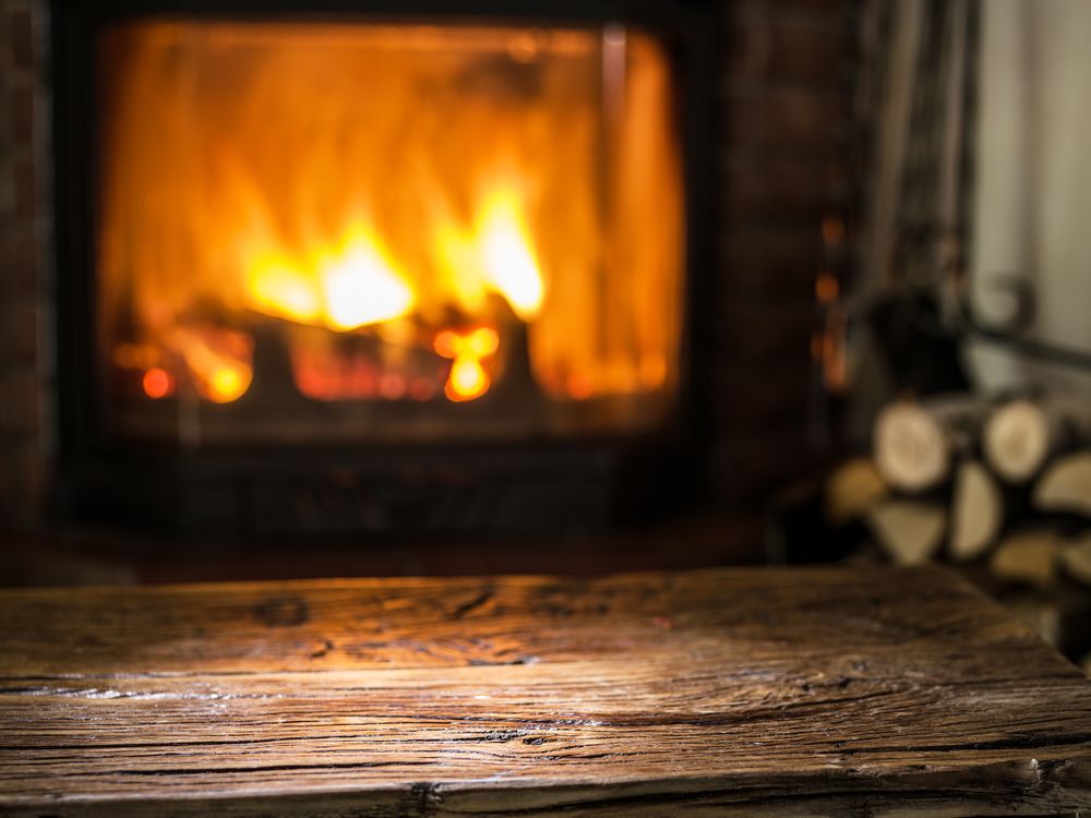A wooden table in front of a warm fireplace