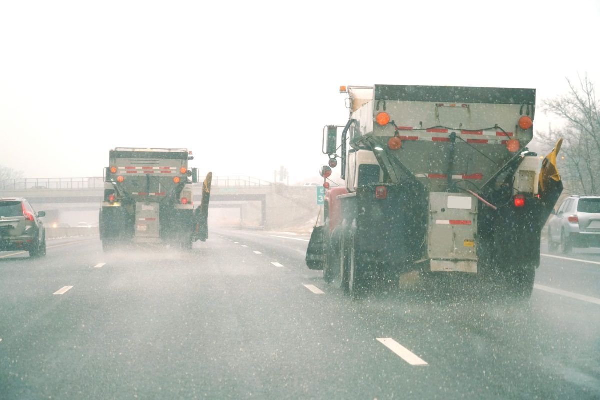 Two snowplows on a highway spreading road salt