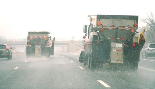 Two snowplows on a highway spreading road salt