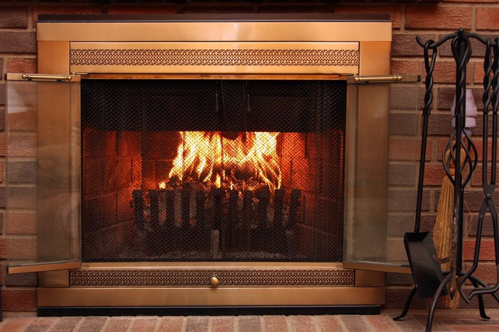 Brass fireplace doors open to show a roaring fire