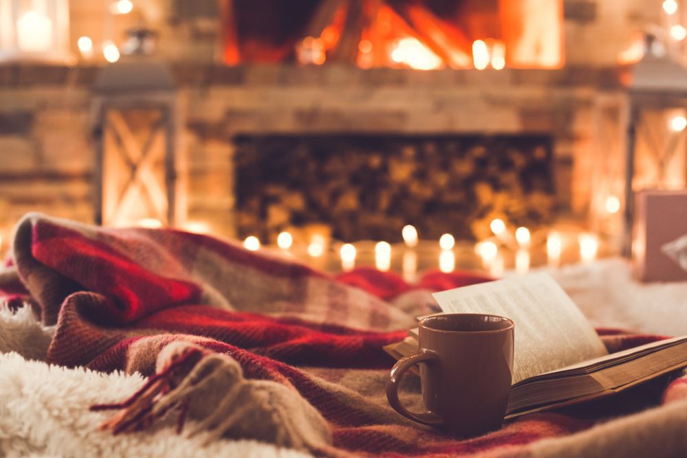 A blanket, a book and a mug in front of a fireplace