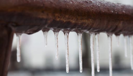 Icicles hanging from a frozen brown pipe