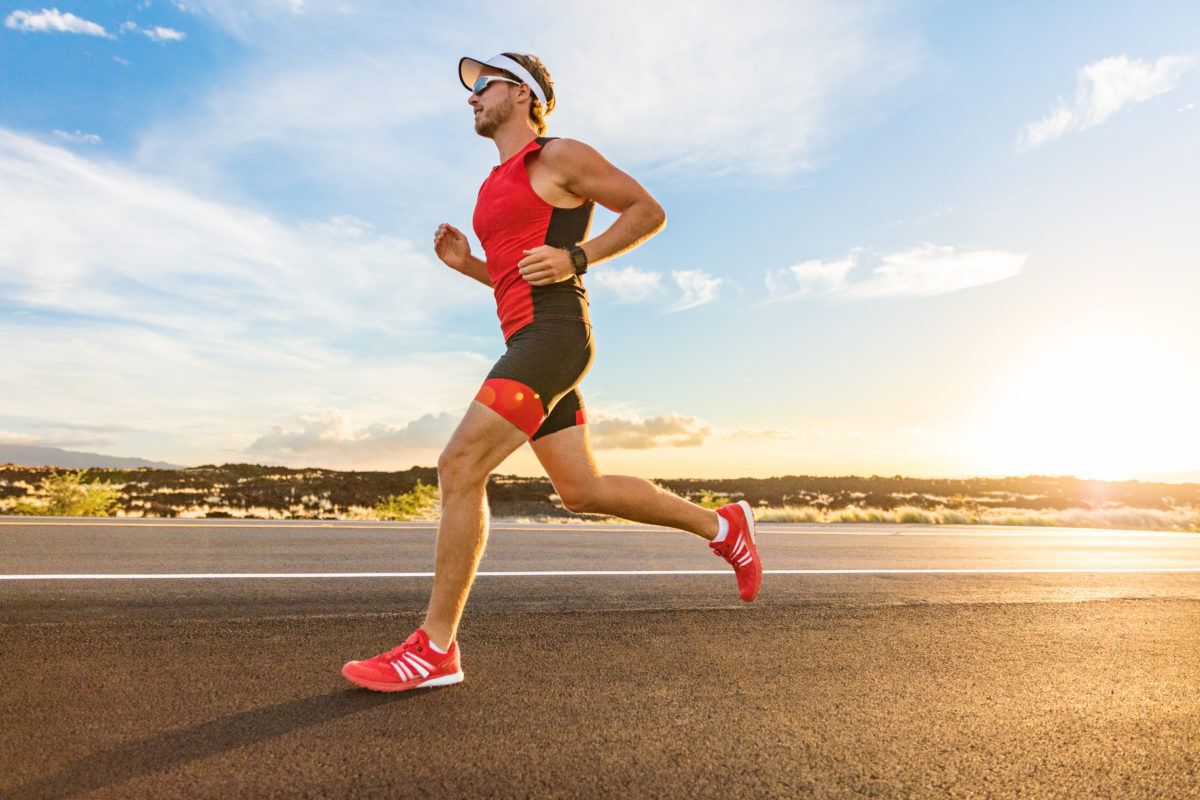 A male triathlon participant running on a beach.