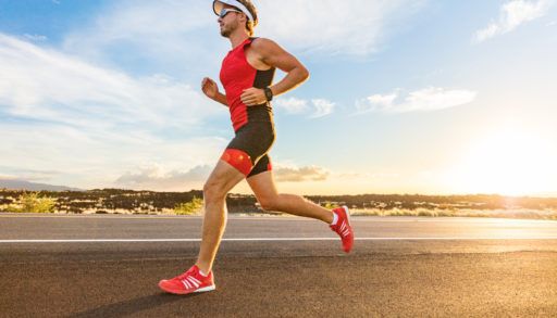 A male triathlon participant running on a beach.
