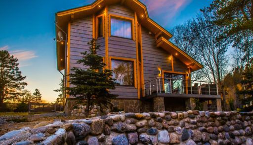 ottage decorated with natural stone. Cottage with balcony. Two-storey house. Wooden house. Living in nature. Finishing natural stone.