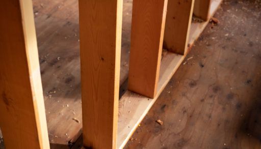 Close up on a row of timber load bearing wall studs, with exposed wood framing, in a home construction background