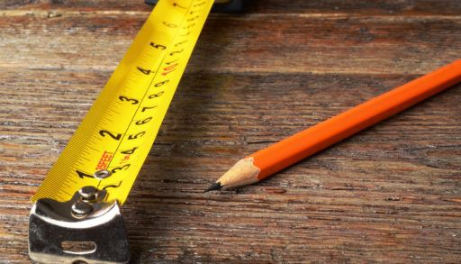 measuring tape on wooden background with red pencil