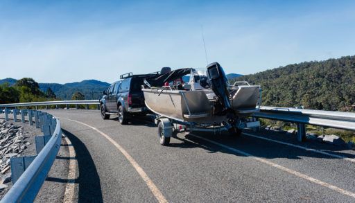 Car tows a boat on a trailer on the highway
