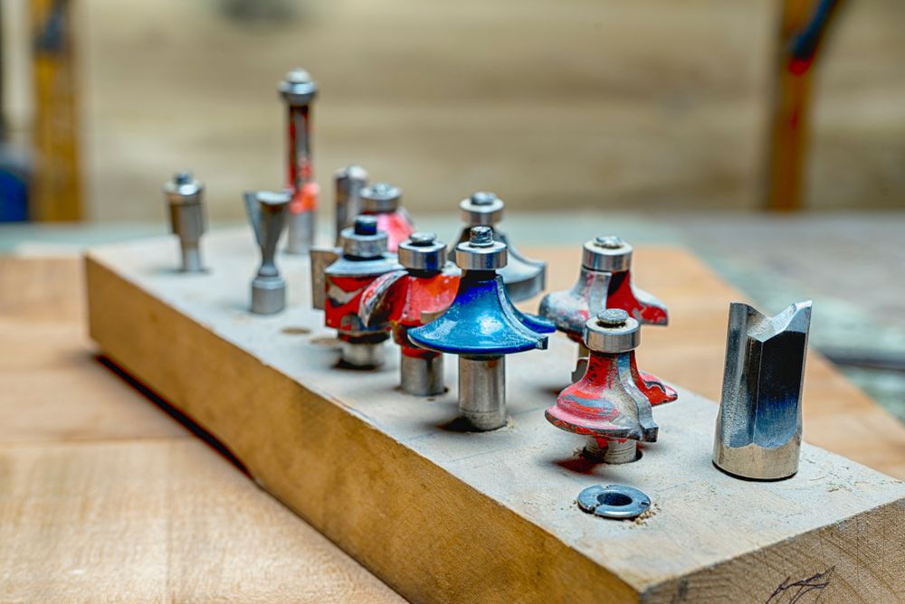 side view of a selection of red and blue woodworking router bits for router machine on a wooden surface