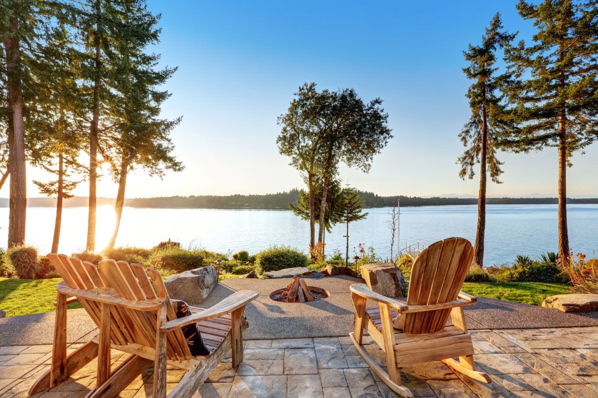 back-yard-of-waterfront-house-with-adirondack-chairs-and-fire-pit