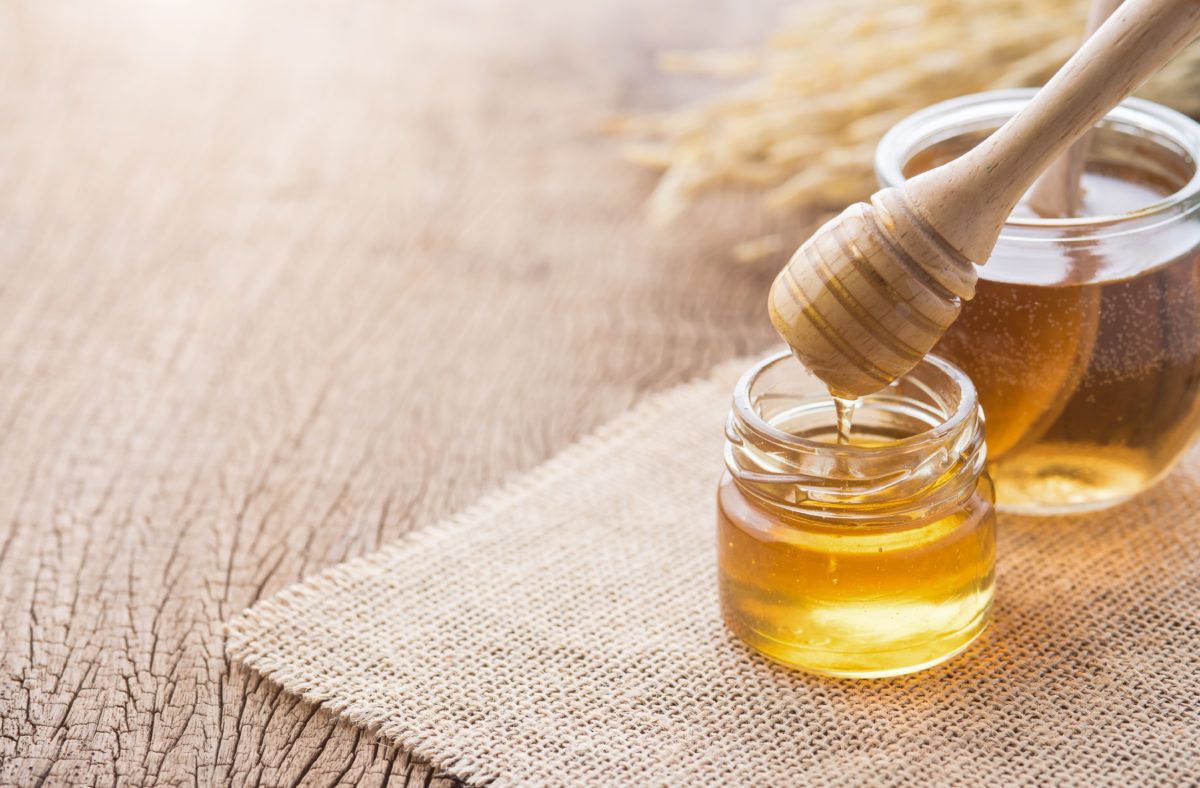 Jar of honey with a wooden honey dripper on a table
