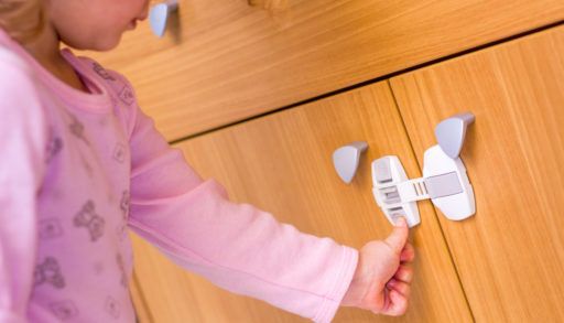 Baby girl trying to open the kitchen cabinet – baby proofing the door