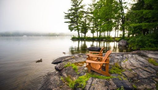 Two cottage chairs on a rocky lakeshore