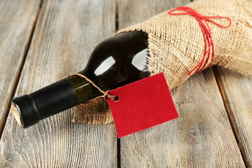 Wine bottle wrapped in burlap cloth on wooden planks background