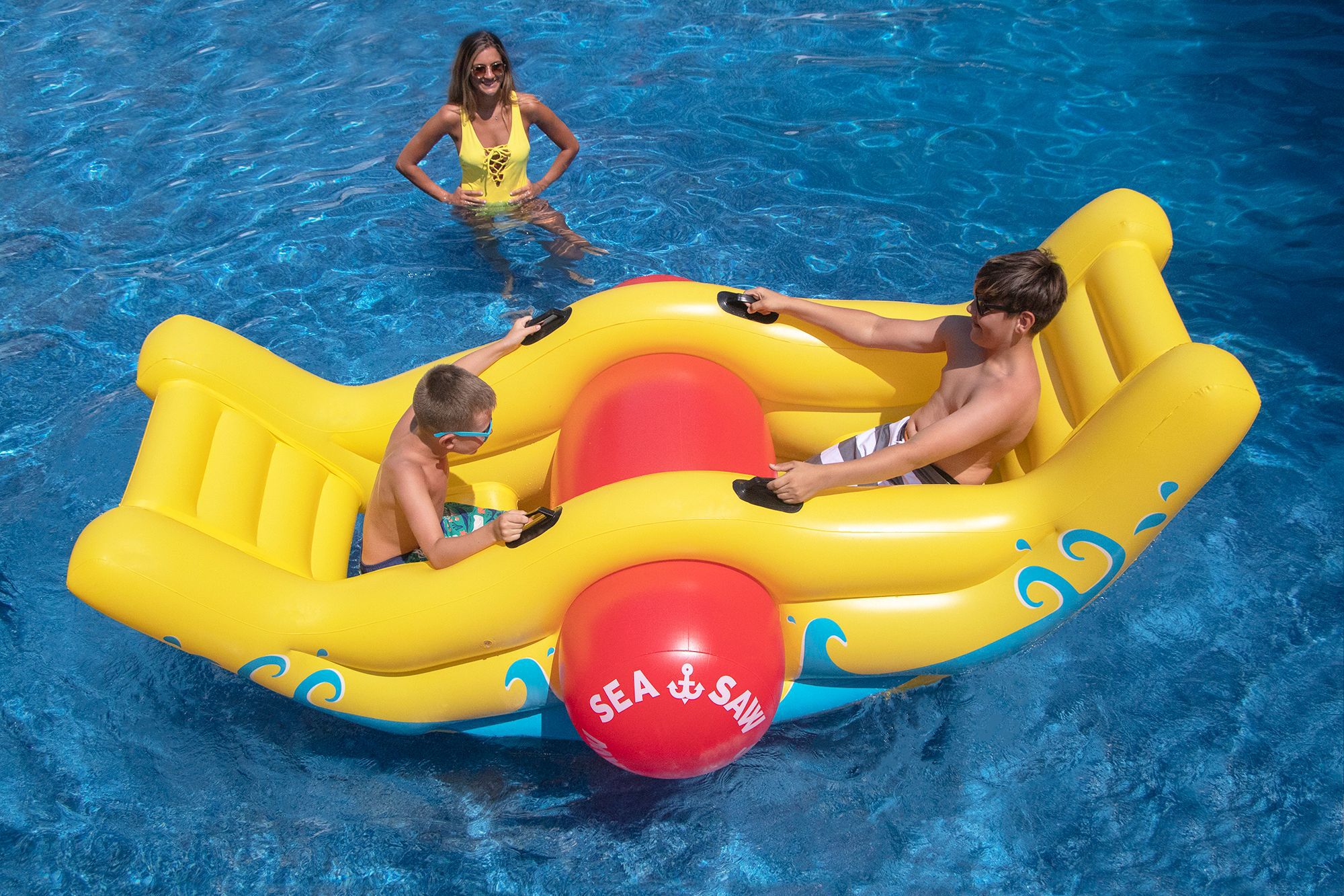 Two boys sit on an inflatable yellow seesaw water toy