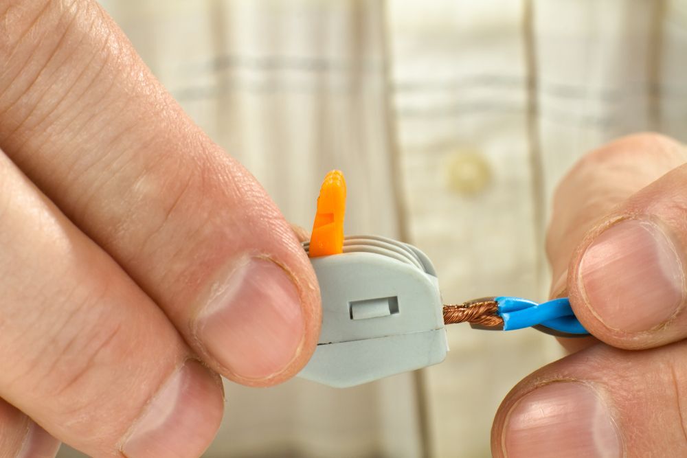 man connects the twisted-together ends of wires using compact splicing connector, closeup