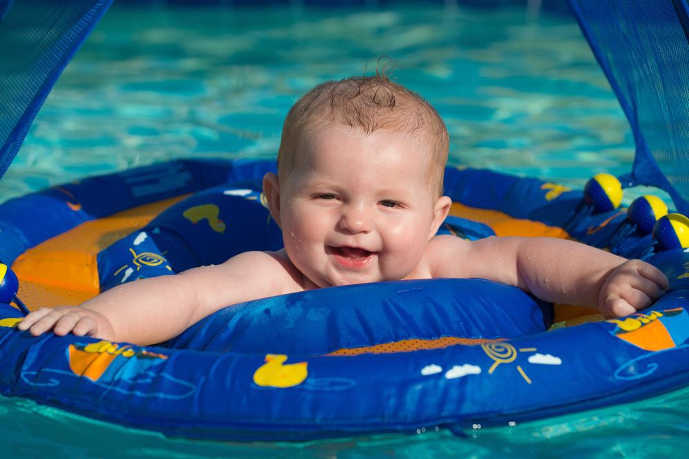 A happy baby sits in a pool float
