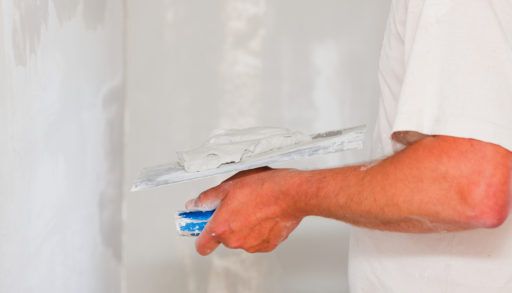 Handyman smoothing drywall before painting when renovation the house.
