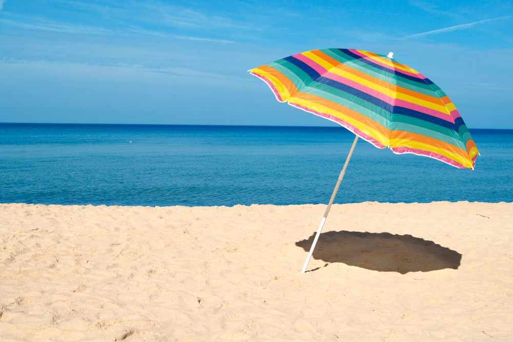 A striped beach umbrella on a sandy beach