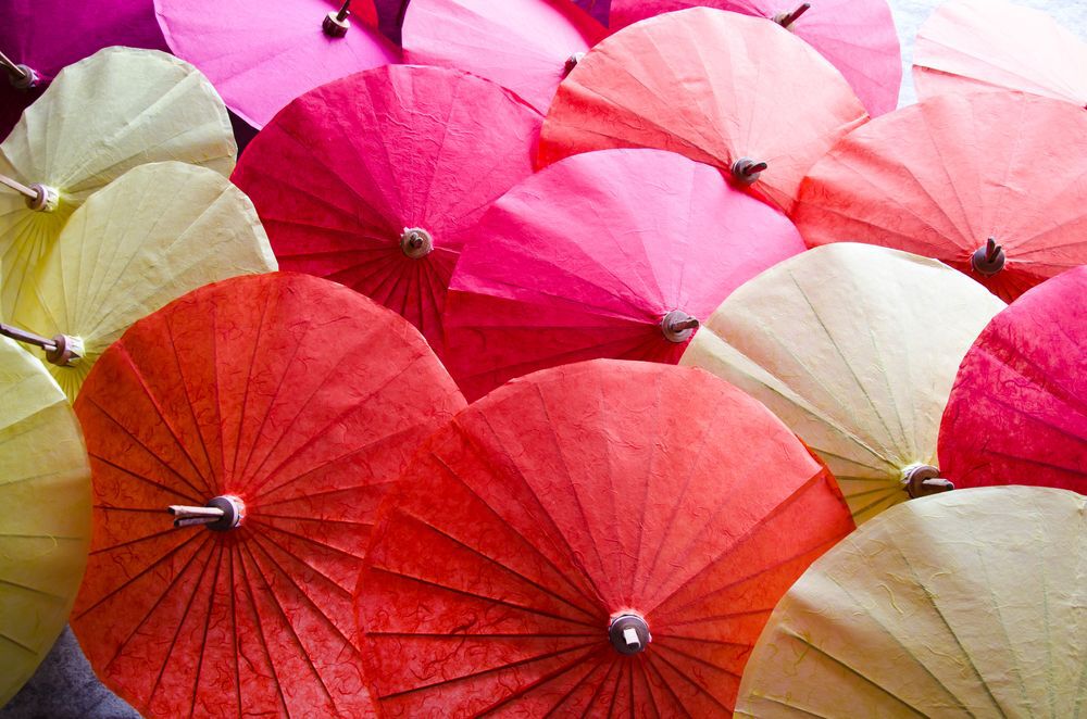 Red, pink and white paper umbrellas open on the ground