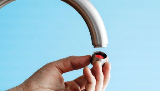 hand unscrews a tap aerator on kitchen tap