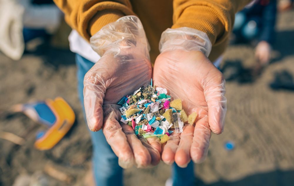 hands-holding-microplastic-particles-on-a-beach