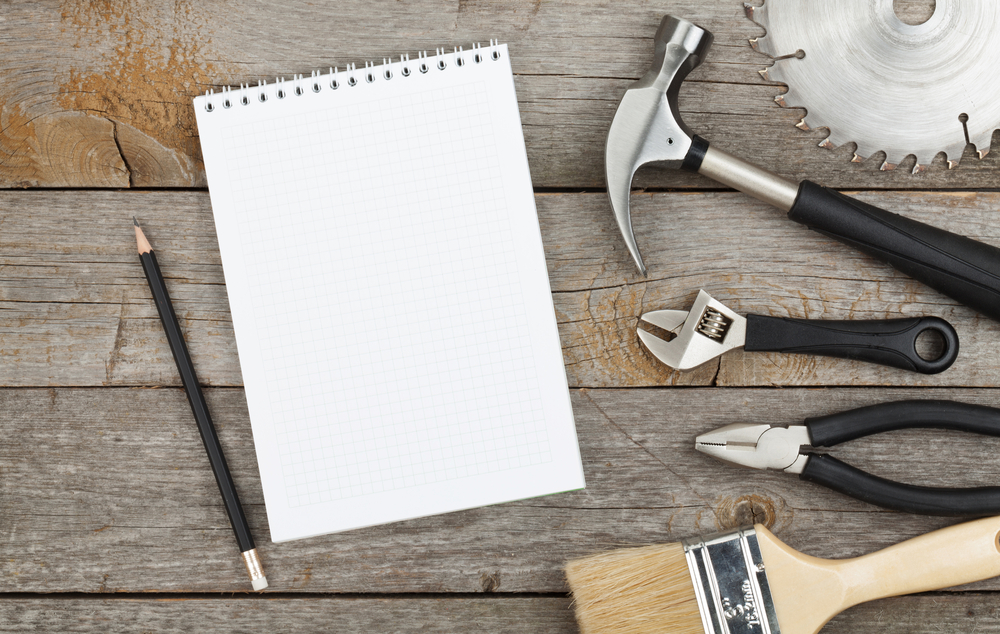 Set of tools on cork panel background with notepad