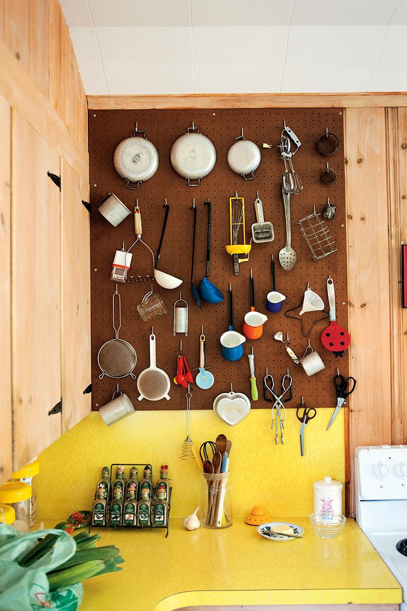 various vintage kitchen utensils hanging on a mounted pegboard