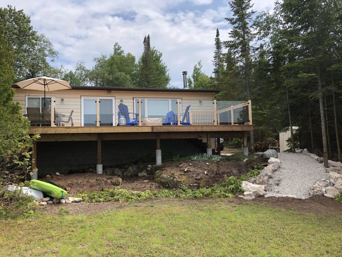Back of single-level cottage with deck