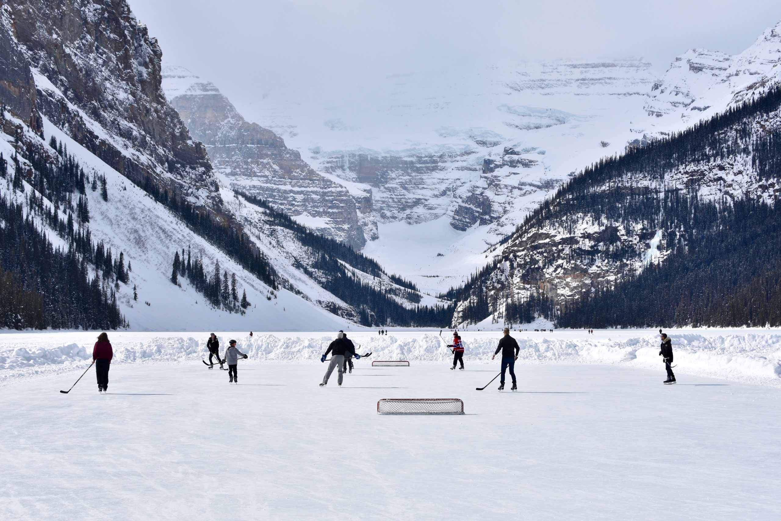 people playing shinny on a frozen lake in the mountains
