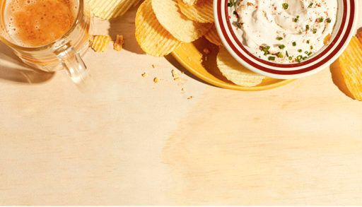 onion chip dip in a bowl with chips and beer