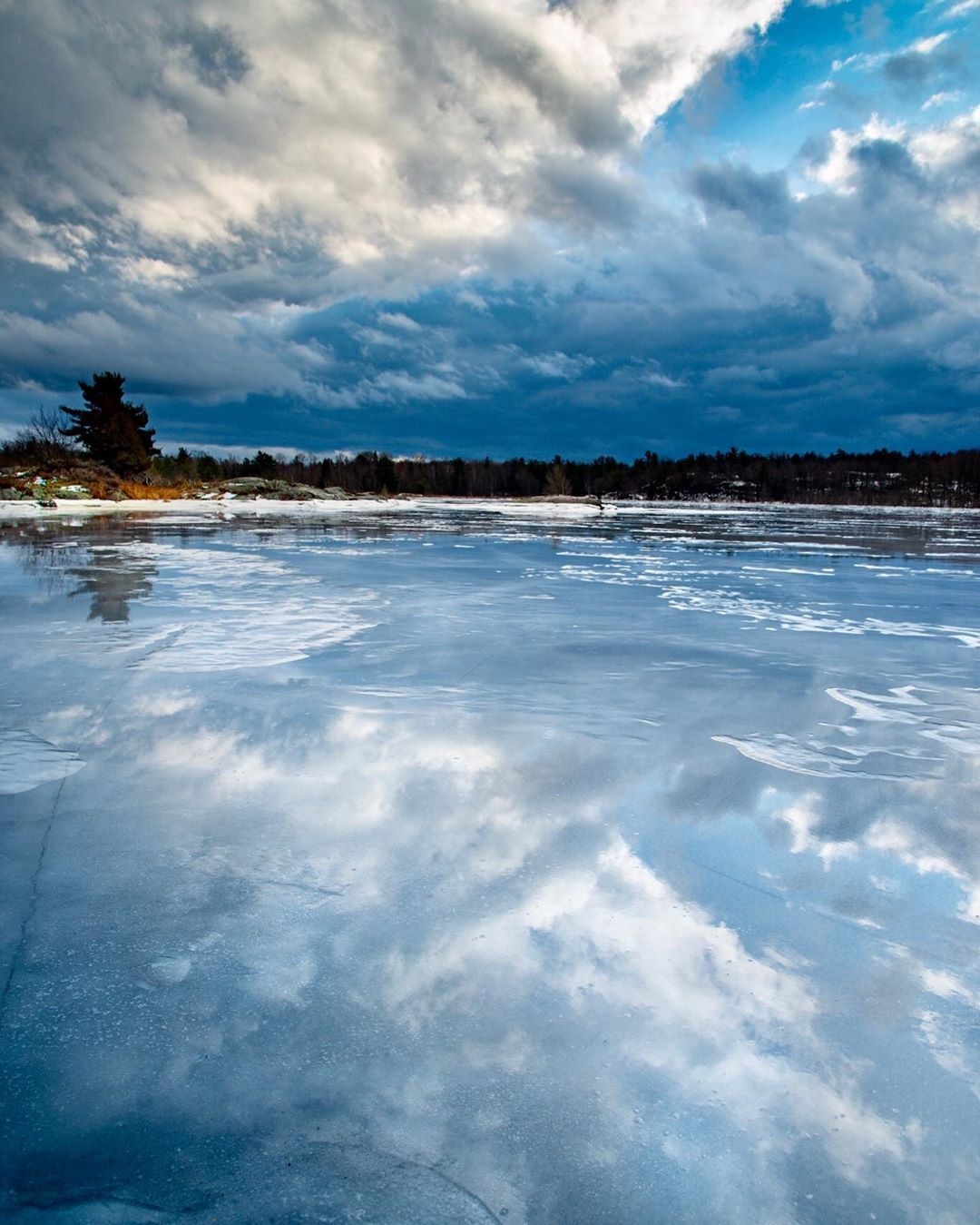 clouds reflecting on frozen lake in winter