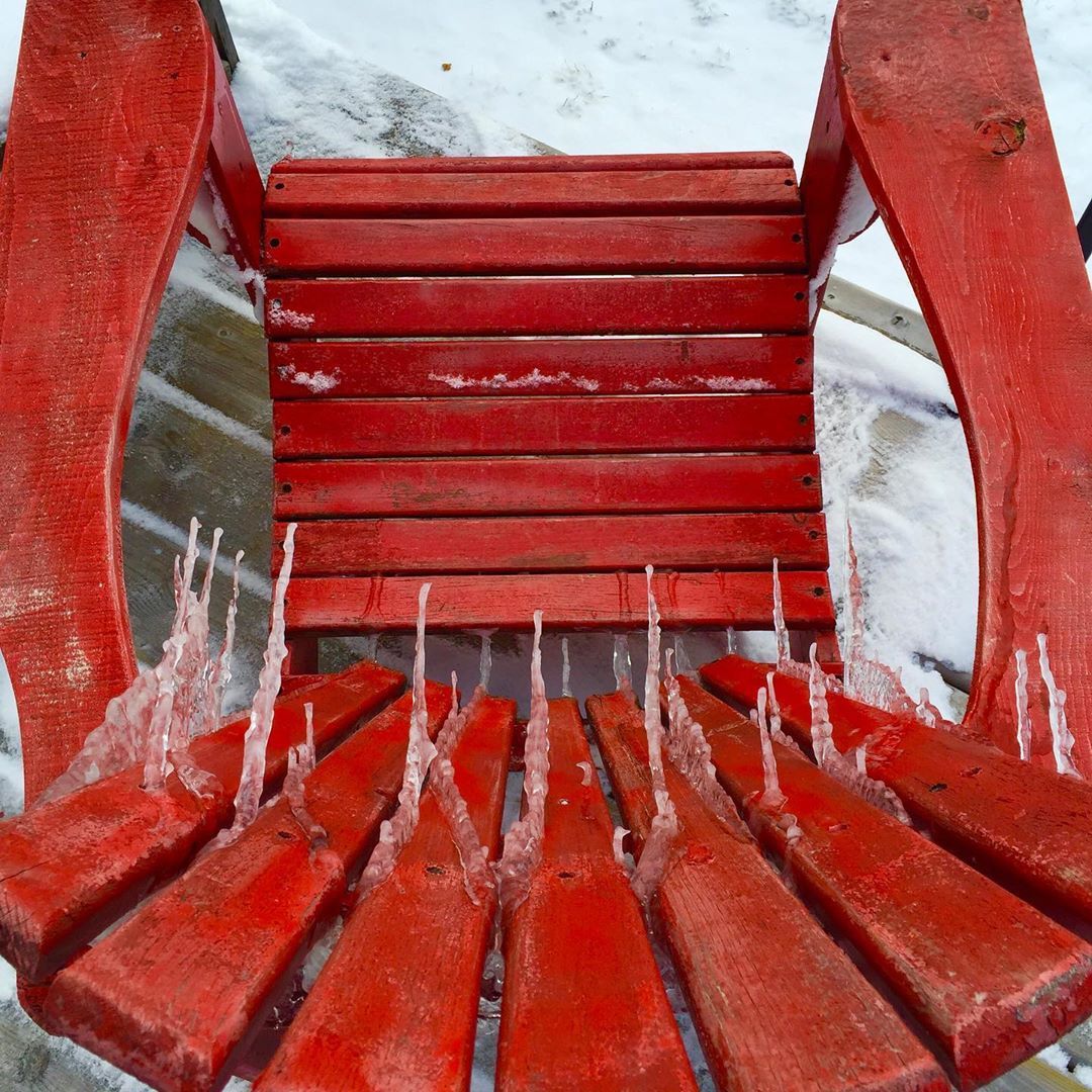 icicles on red muskoka chair in winter