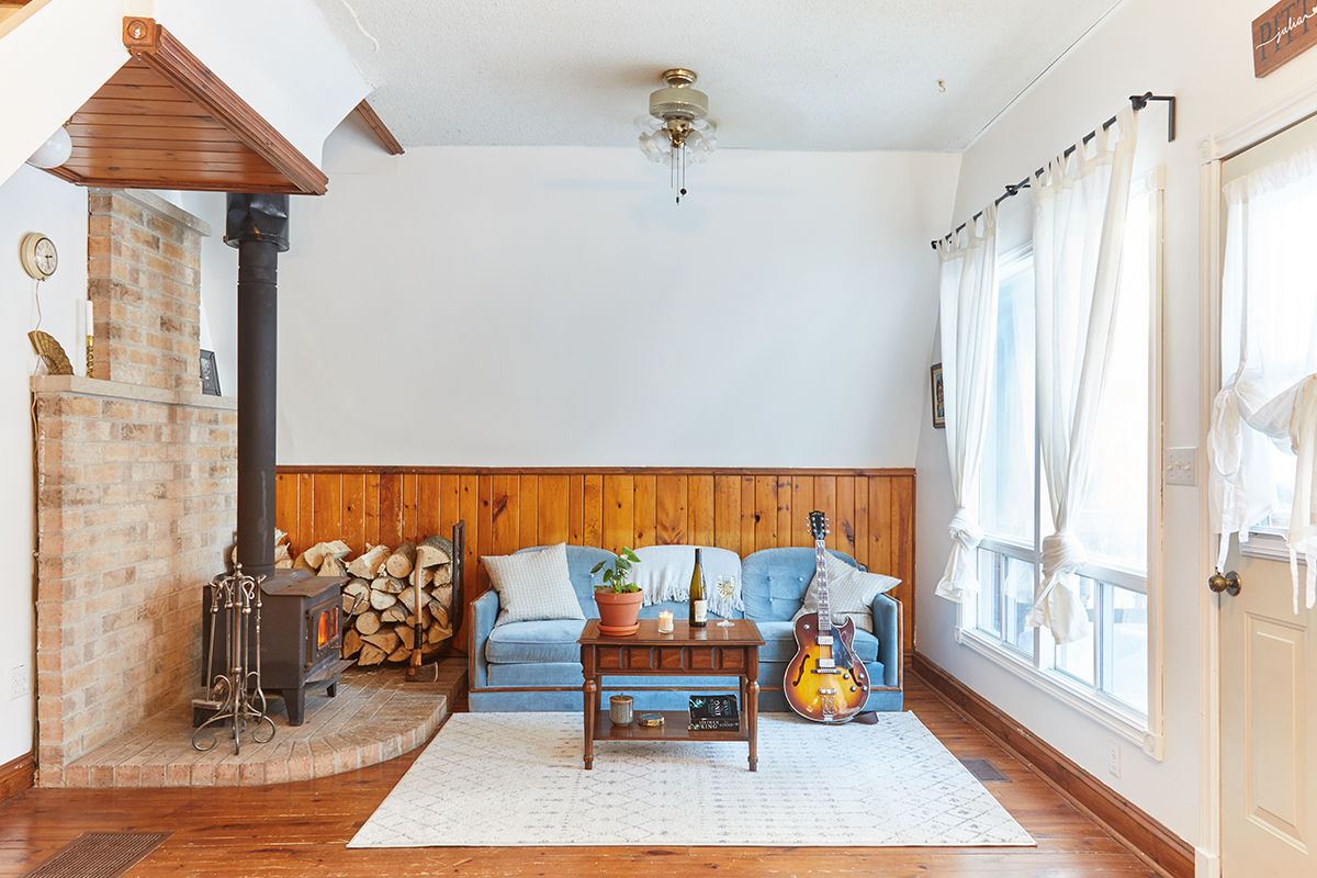 blue velvet couch in a-frame living room next to a woodstove
