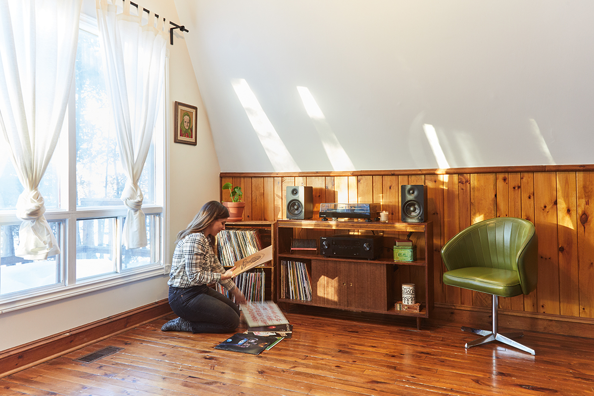 Julia sitting in front of record player on a credenza in the a-frame living room