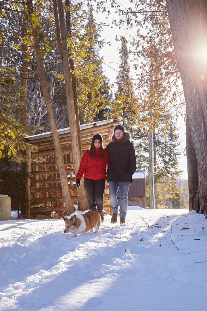 Julia and Adam walking outside the a-frame with Burger, their corgi