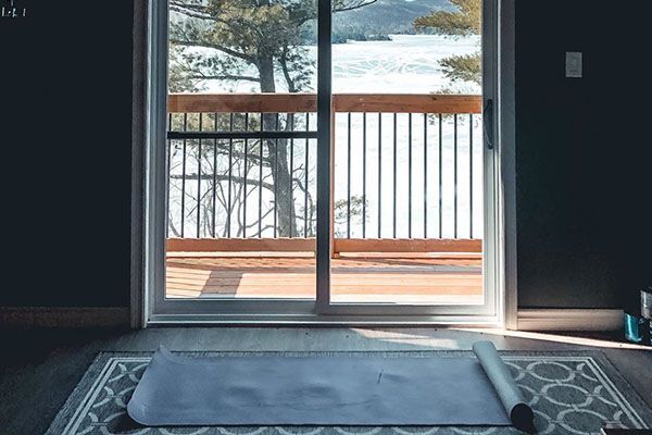 yoga mat on rug, looking through sliding door out onto a frozen lake, self isolation