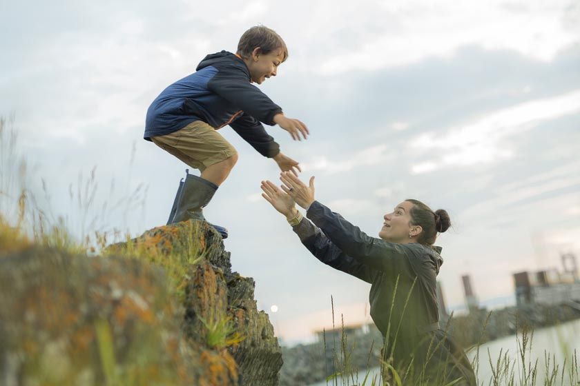 a kid jumps into his mother's arms in nature