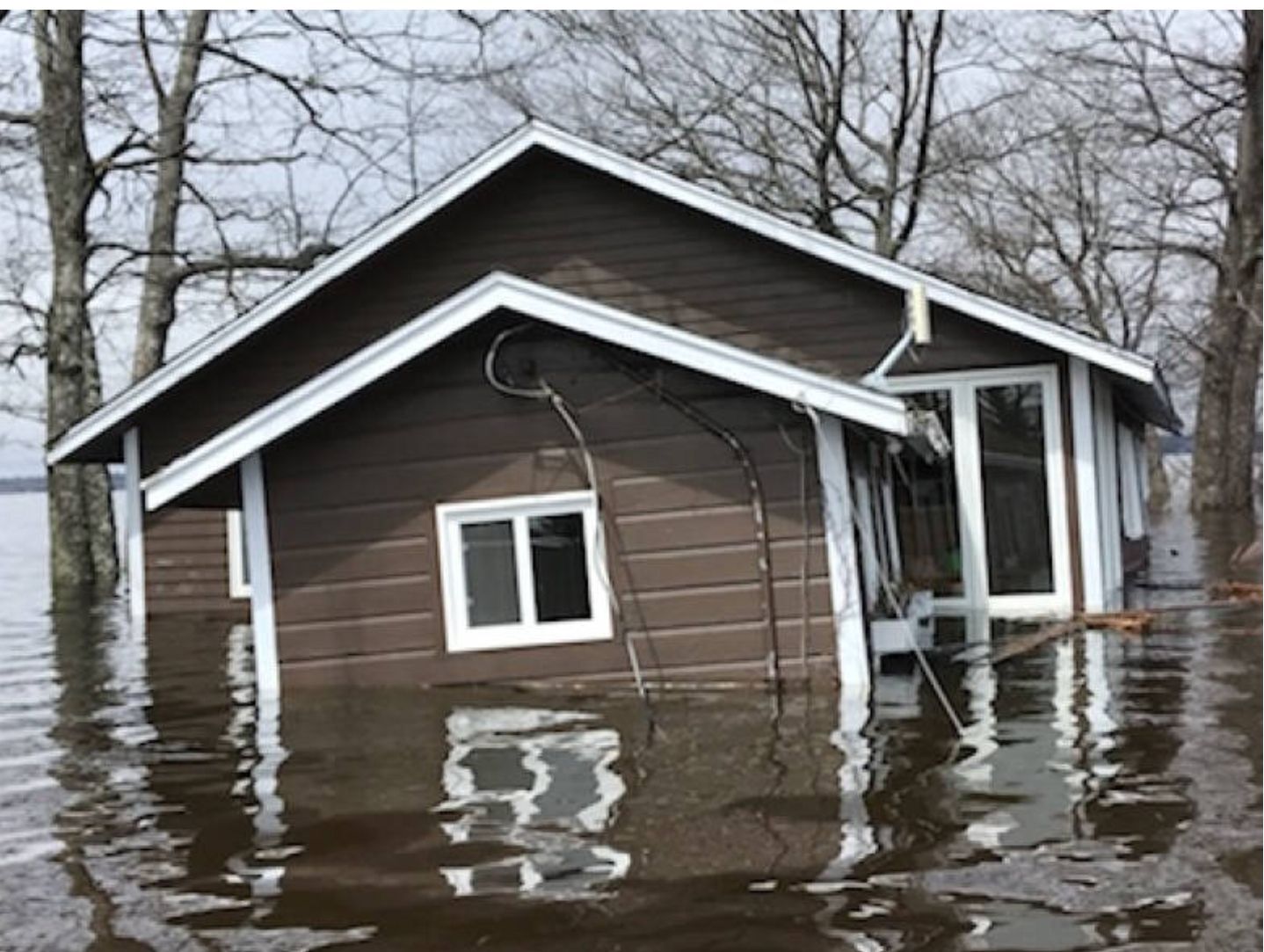 A cottage is half submerged in flood waters