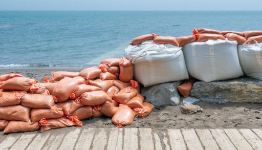 Plastic flood protection sandbags stacked into a temporary wall along lakeshore